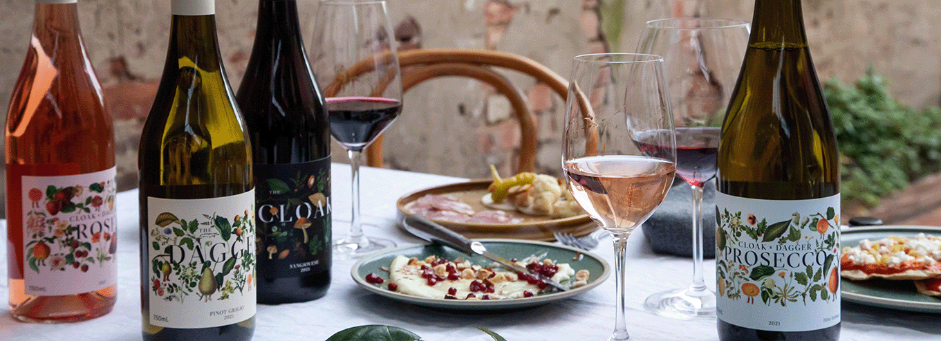 Table with Cloak & Dagger wine bottles and food  